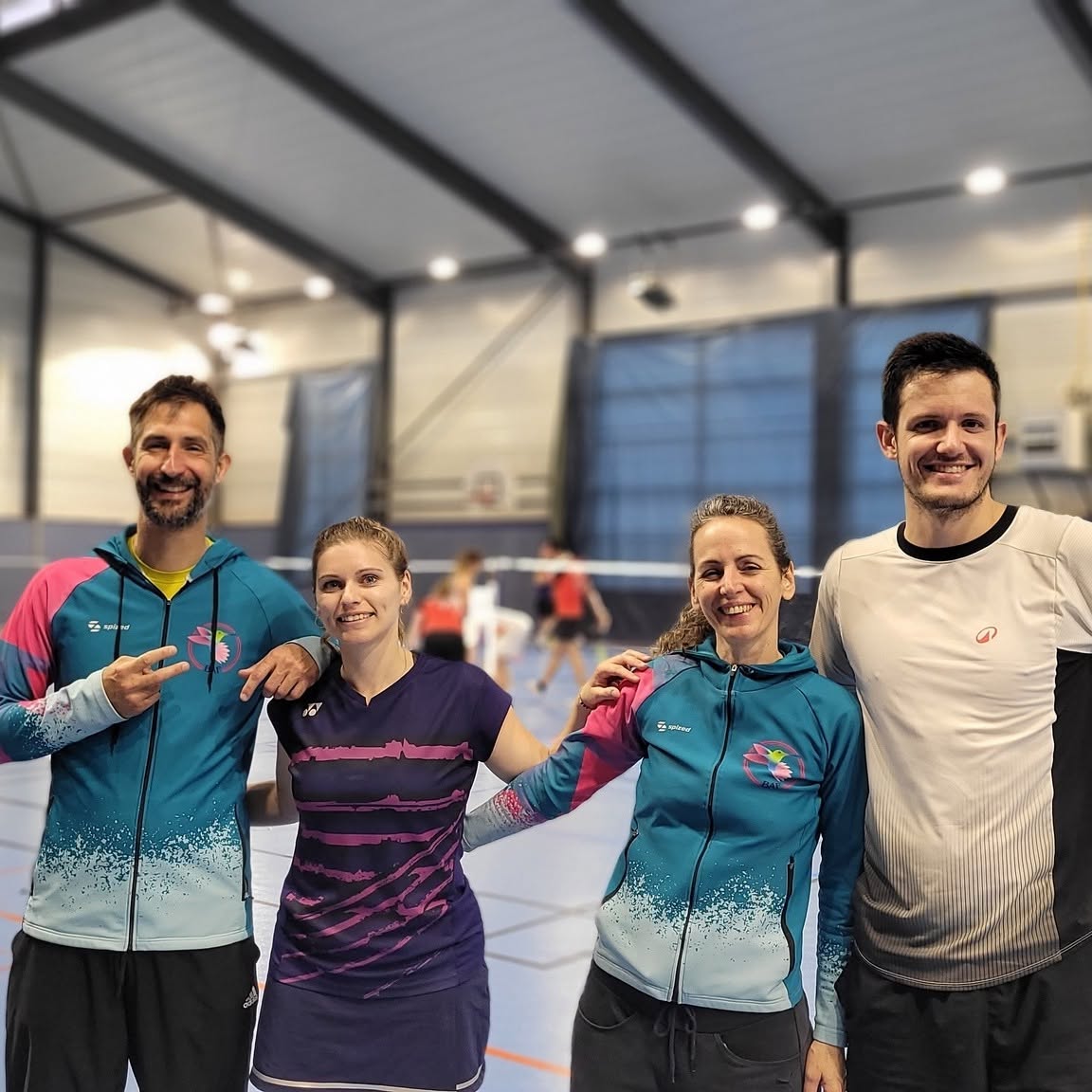 Quatre joueurs de badminton réunis sur un terrain, dont deux portent les couleurs de Badaflo