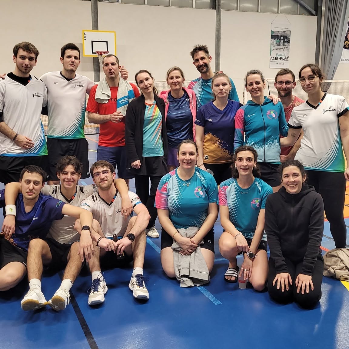 Un groupe de joueuses et joueurs réuni dans un gymnase, plusieurs portant le maillot turquoise de Badaflo